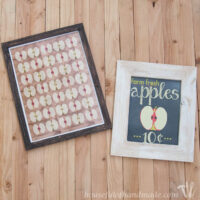 Two fall apple signs in frames laying on a wood background.