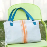 Handmade purse made from drop cloth with orange painted grain sack stripes and blue handles.