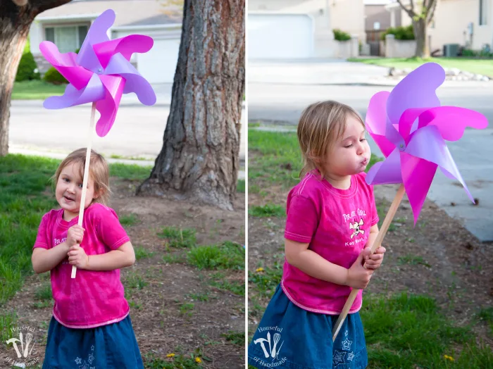 little girl in pink shirt and jean skirt playing with completed pink and purple pinwheel