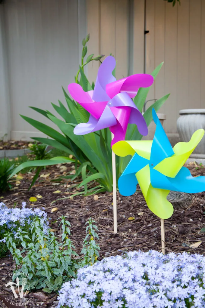set of two completed pinwheels in the garden one is pink and purple and one is yellow and blue