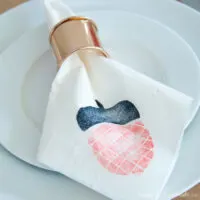 Acorn stamped decorative napkin in a rose gold napkin ring on a white plate.