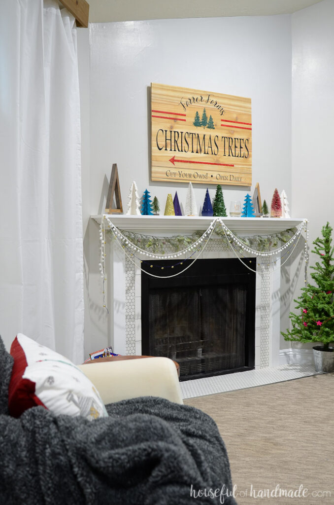 Living room decorated for Christmas with a DIY tree farm sign and lots of decorative Christmas trees.