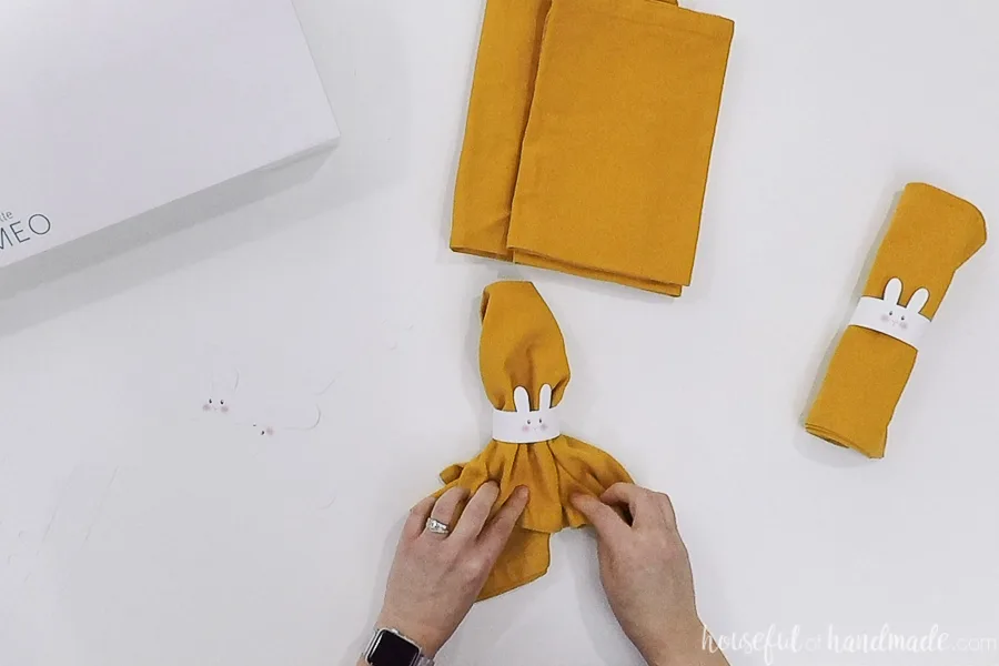 Straightening the yellow cloth napkin in the napkin ring. 