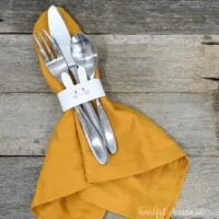 Bunny napkin ring around a napkin with silverware tucked inside.