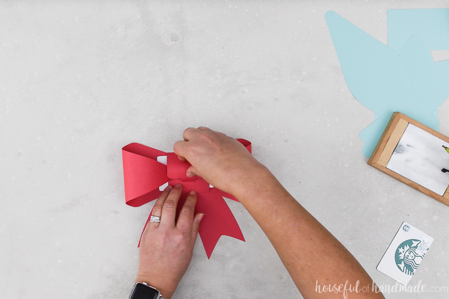 Red paper bow gift card holder being folded around an Amazon gift card.