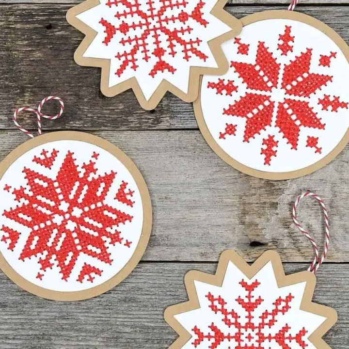 Four handmade Christmas ornaments with cross-stitched design on them.