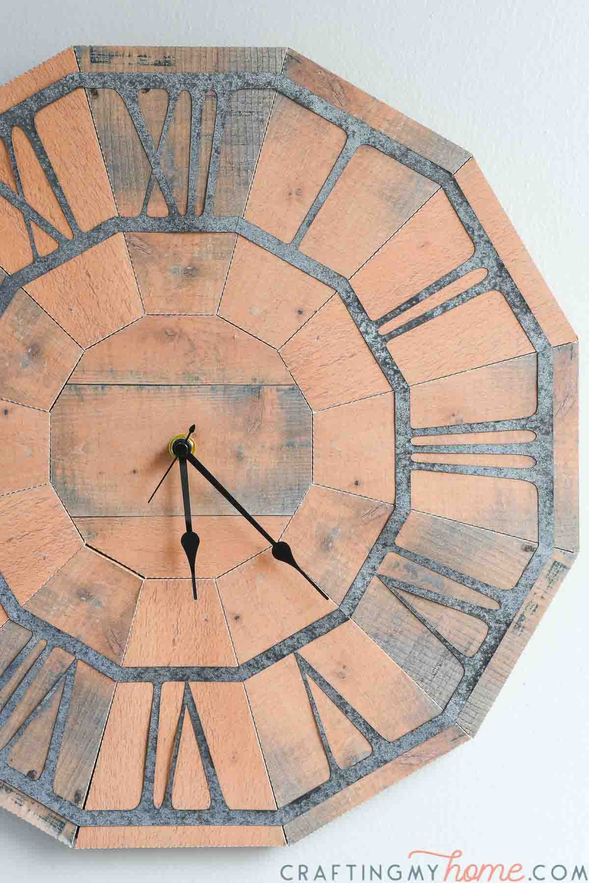 Rustic wall clock made hanging on a pale gray wall.