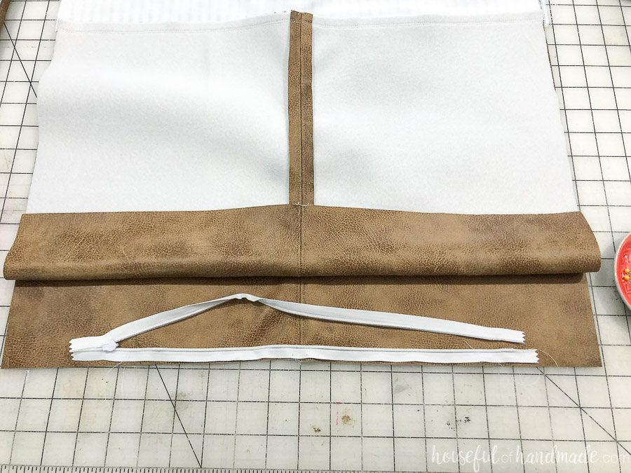 One half of the invisible zipper sewed to the DIY leather pillow cover and figuring out how to properly attach the other side.
