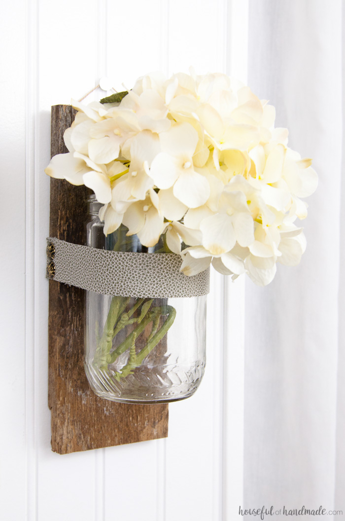 White hydrangea in the wall vase hanging on the wall. 