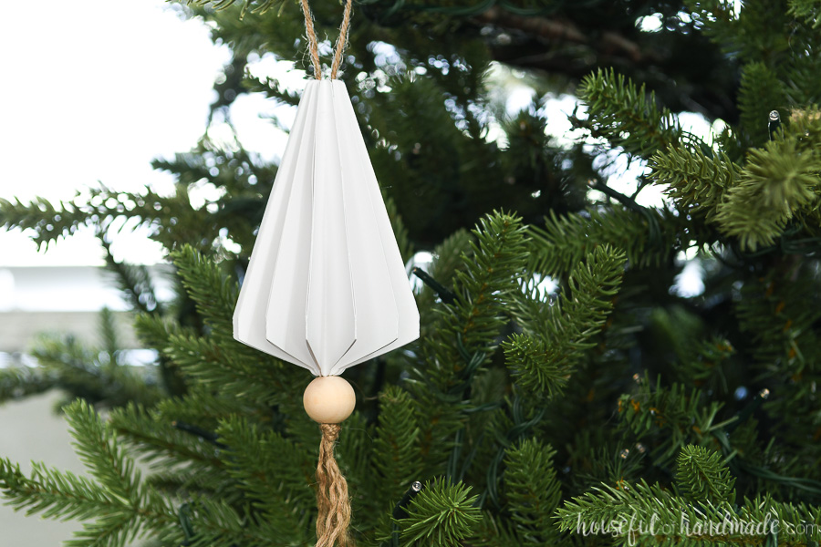 Christmas tree without lights and a white paper tree triangle shaped jewel shaped Christmas ornament hanging on it.
