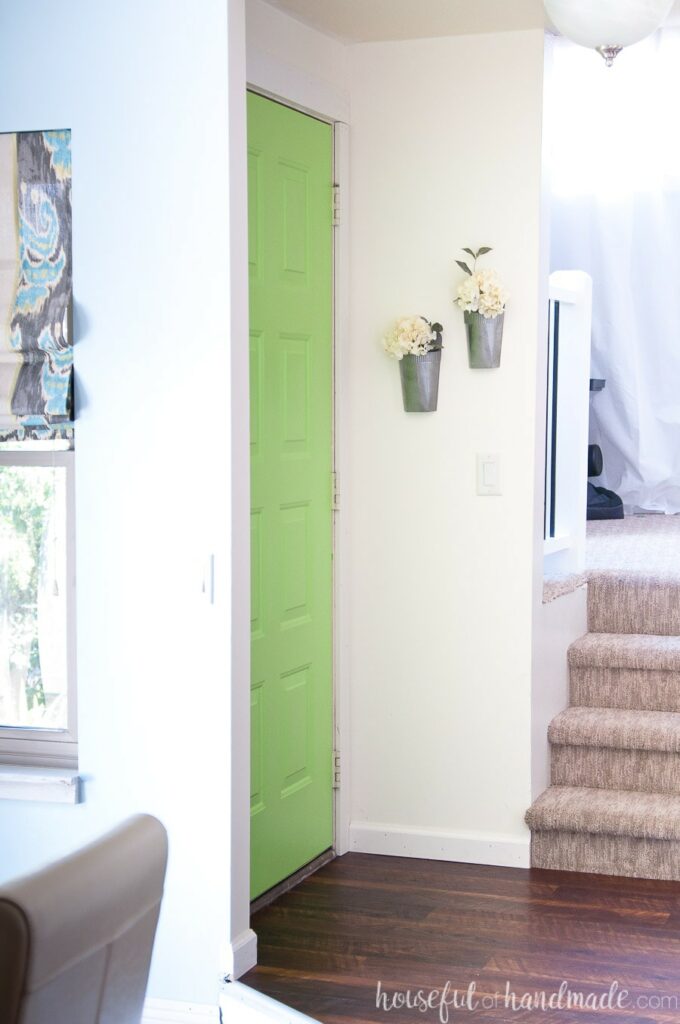 Entryway in the home with green door and faux metal wall vases hanging on the wall. 