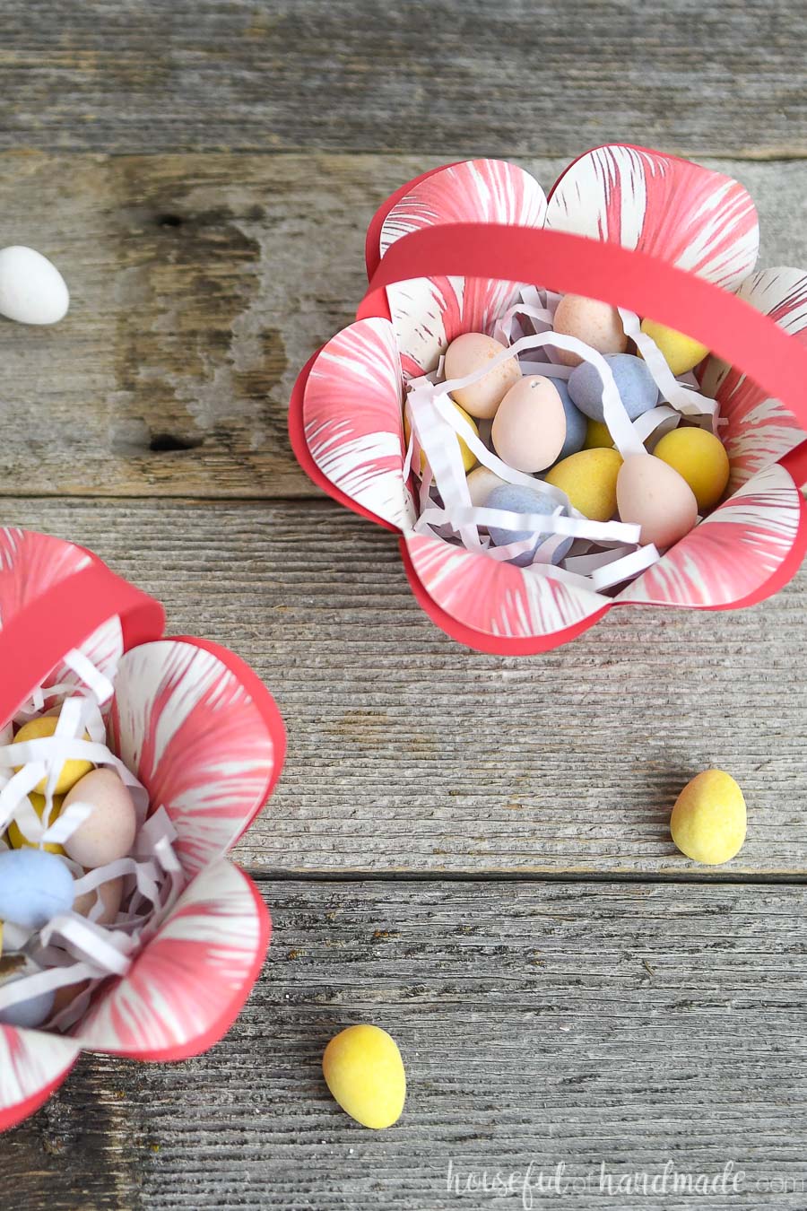Two paper easter baskets that look like flowers filled with shredded paper and egg candies.