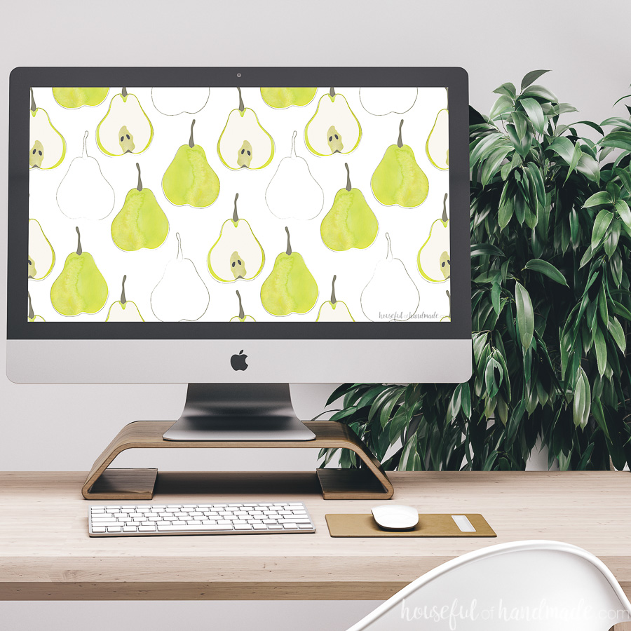 Green pear digital wallpaper as the background on an iMac computer on a desk.