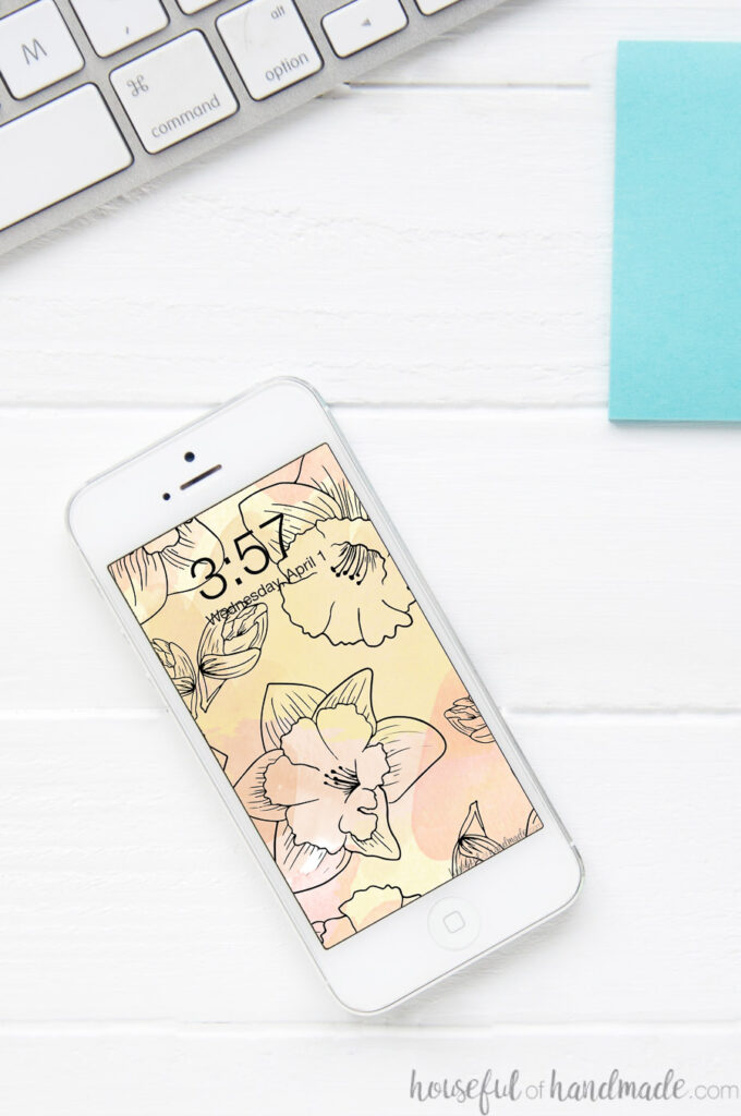 White iPhone with watercolor daffodils pattern as the digital wallpaper on the home screen.