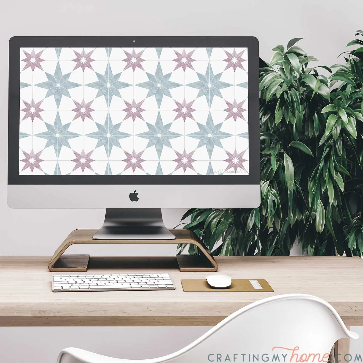 The free digital background for March on the screen of an iMac computer sitting on a desk with a plant behind it. 