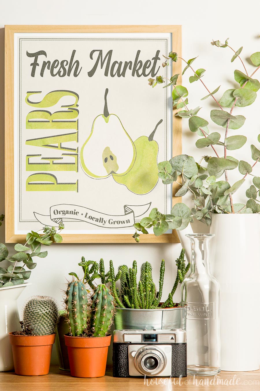 Fall vignette with printable farmers market sign surrounded by plants in pots and vases. 