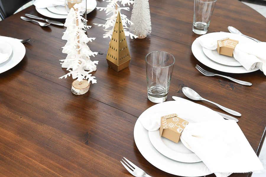 Looking on top of a table set for Christmas with Christmas trees and gingerbread house napkin rings. 
