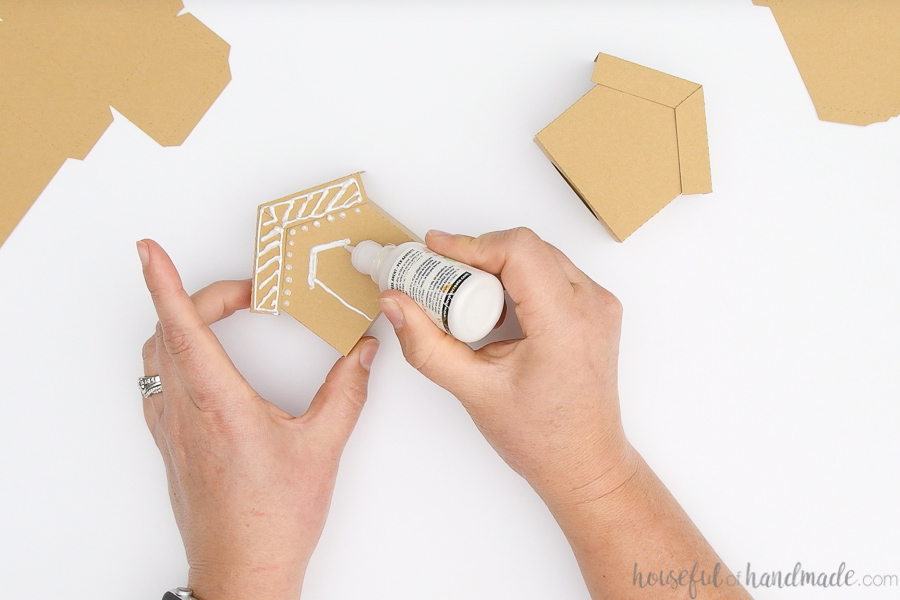 Decorating the front of the paper gingerbread houses with white puffy paint.