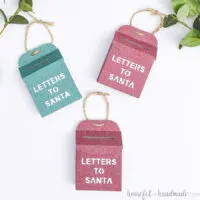 Three glittery Letters to Santa mailbox ornaments on a white background.