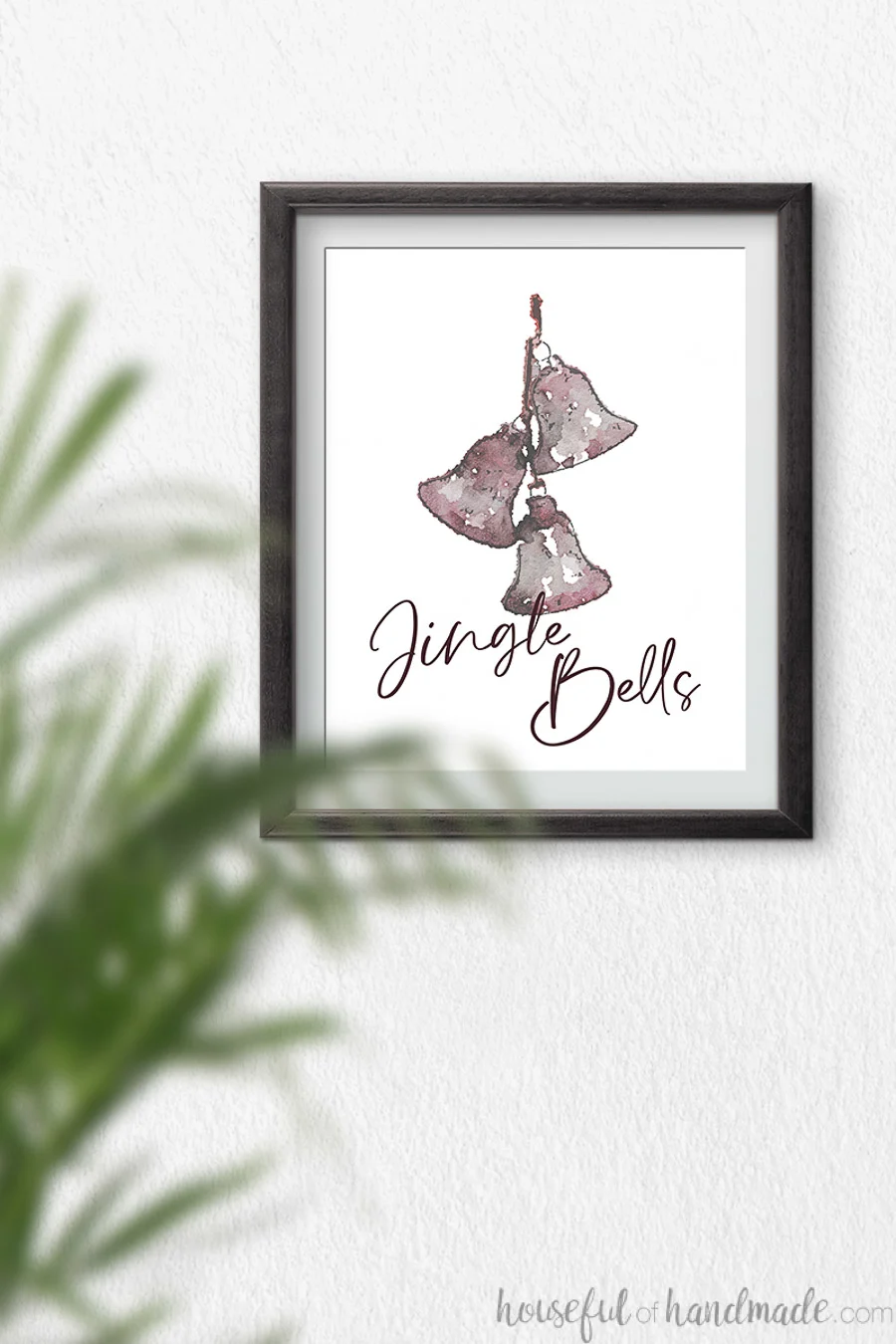 Watercolor of three reddish jingle bells hanging on a string with script writing Jingle Bells over the bottom of it.