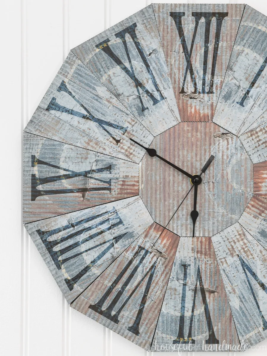 Rusted blue steel clock made out of paper hanging on a beadboard wall. 