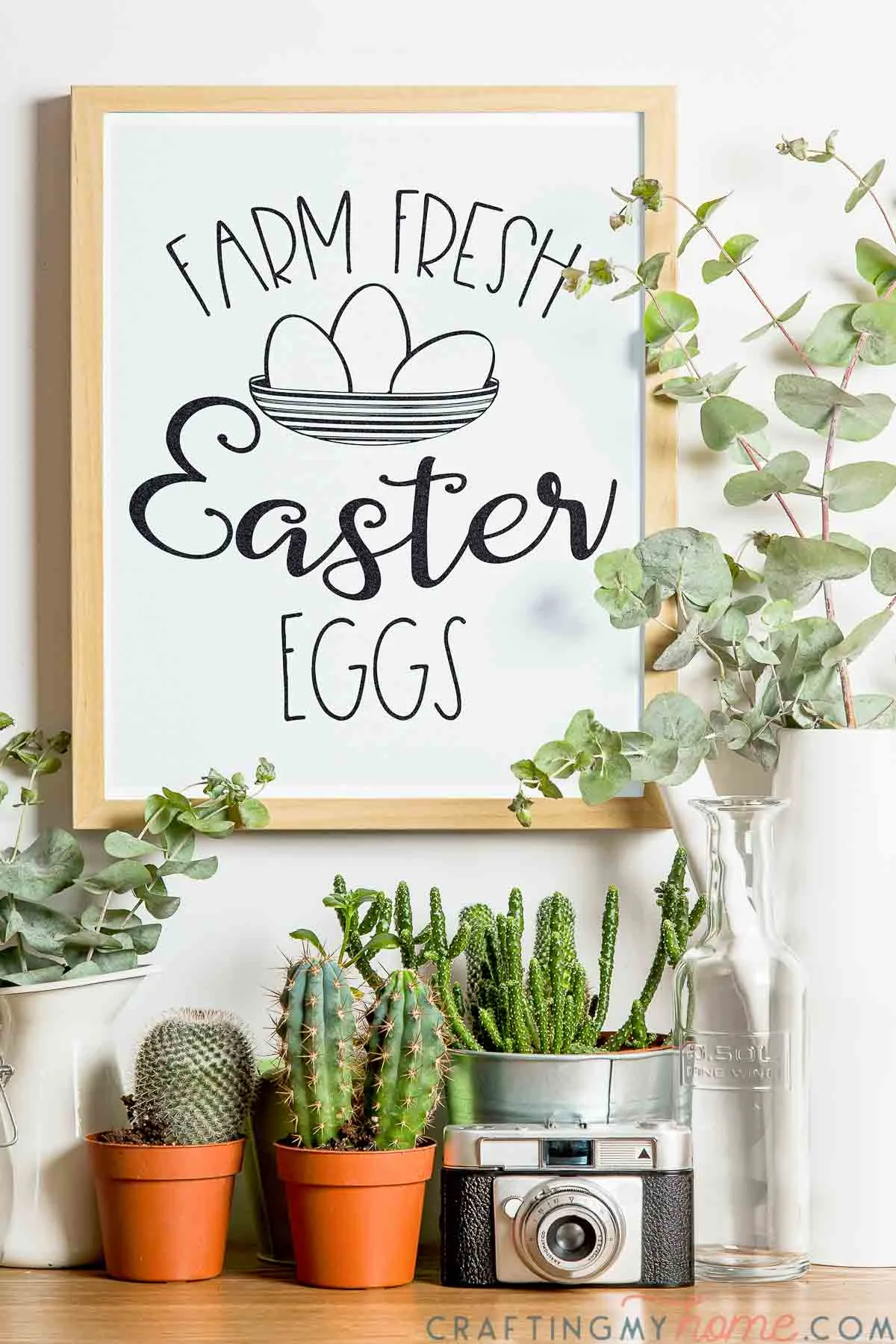 Console with plants on it and frame hanging on the wall above it with the beautiful Easter egg sign in it.