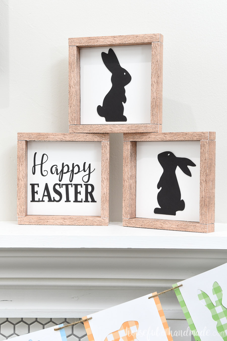 Three farmhouse Easter signs stacked in a pyramid on a shelf.