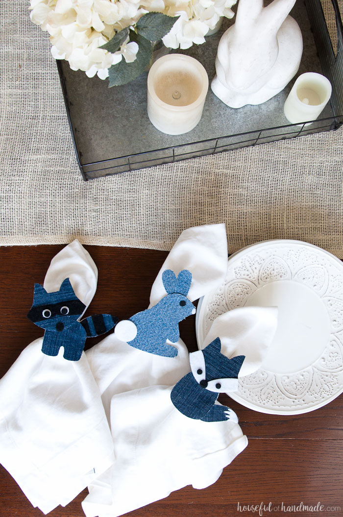 Three napkin rings made from paper and upcycled denim in woodland animals with white napkins inside them. 