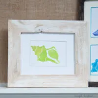Custom photo mat with printable watercolor seashell in a frame on a mantle