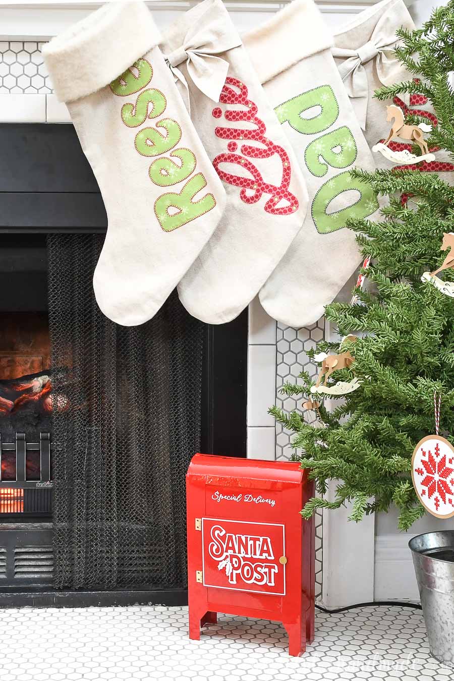 Fireplace hearth decorated with small tree, personalized stockings and red DIY Santa mailbox. 