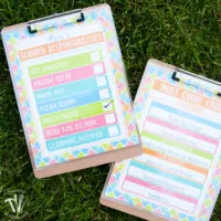 Two printable summer chore charts on clip boards on grass