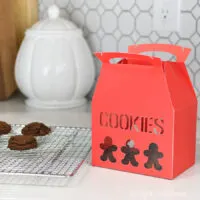 Red Christmas Cookie box with cutout gingerbread cookie shapes for decor.
