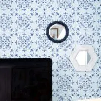 Two wall mirrors, one white hexagon and one blue geometric, hanging on a blue and navy stenciled wall.