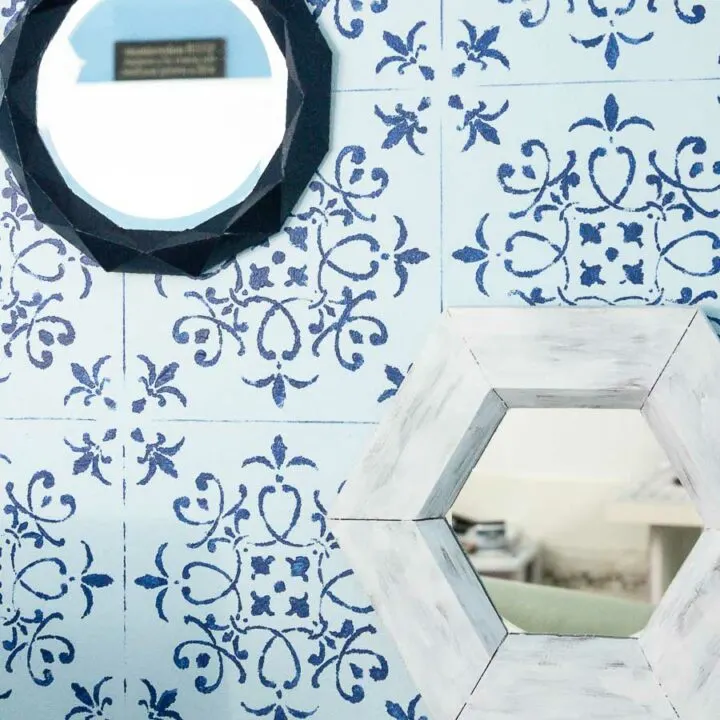 Hexagon wall mirror hanging on a stenciled wall next to another paper wall mirror.