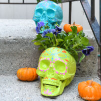 Porch with 2 DIY sugar skull planters on it with fall flowers in them.