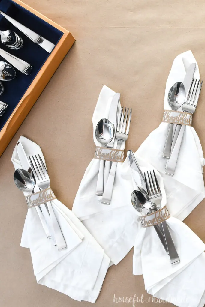 set of 4 white napkins with diy paper napkin rings and silverware