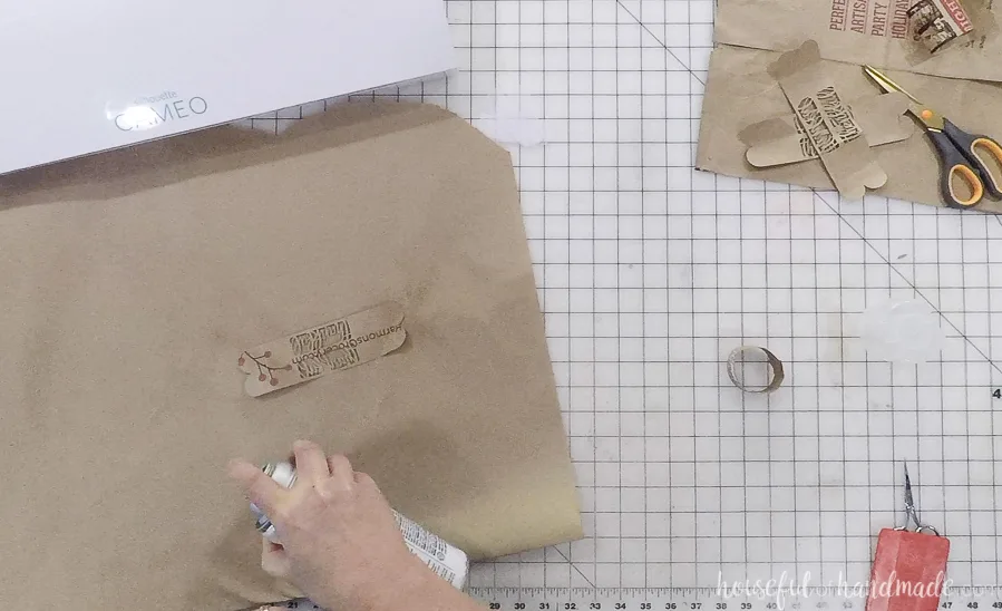 spraying adhesive glue on paper bag for diy thankful napkin rings