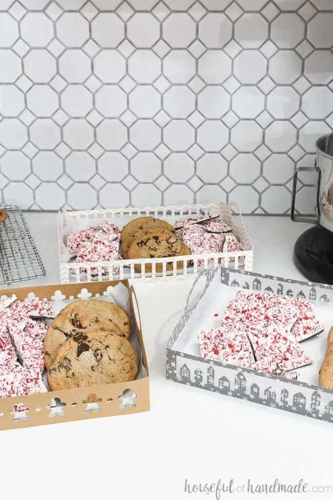 3 paper christmas cookie trays on counter with hexagon background