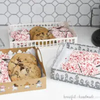 Three DIY paper trays with Christmas designs on them filled with treats.
