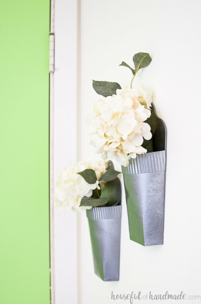Side view of the DIY wall vases hanging on the wall filled with white hydrangea flowers. 