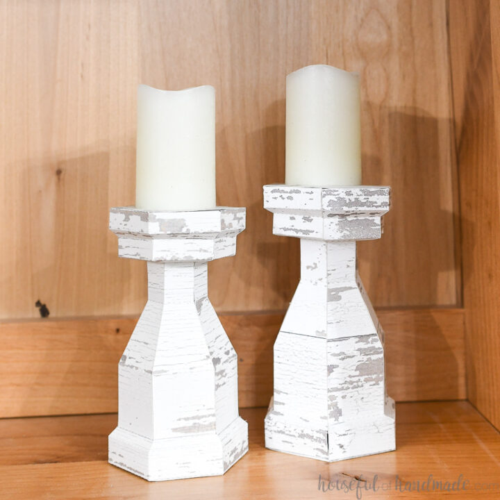 Two fab wood candlesticks with white candles on them.