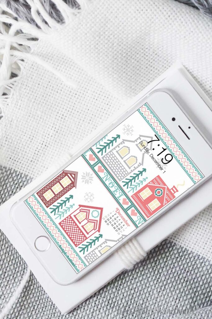 White iPhone showing the Christmas cross-stitch village design on the background. 