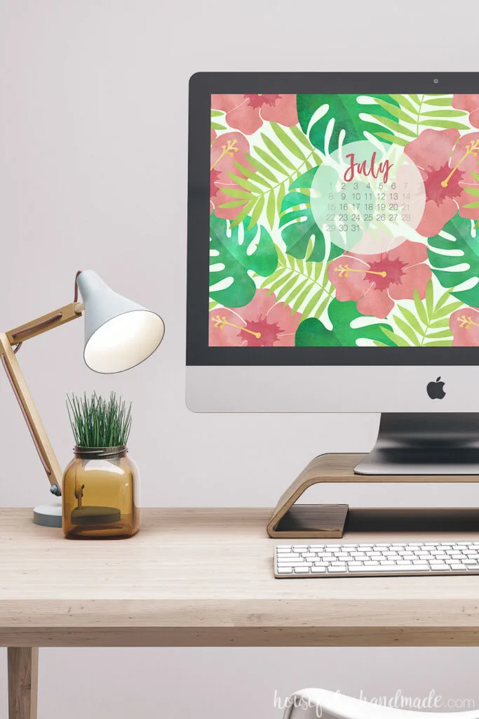 iMac on a desk with lamp displaying water color digital wall paper with a calender.