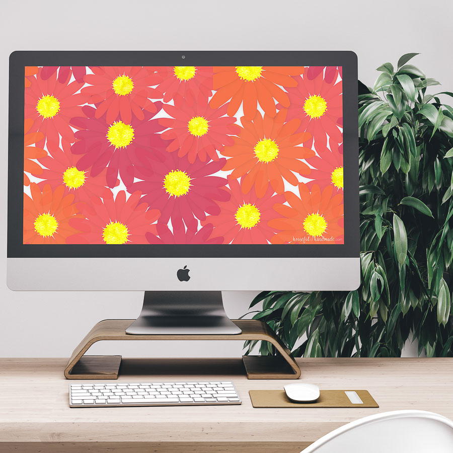 Computer on the desk with colorful floral digital wallpaper on the screen. 