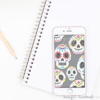 Smartphone with sugar skulls on a gray digital background sitting on a notebook.