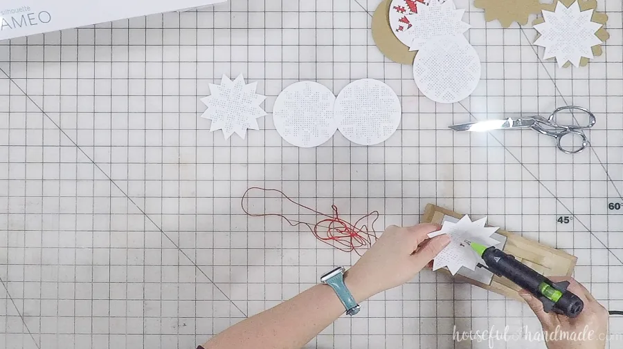 hot glue gun being used on nordic cross stitch ornaments