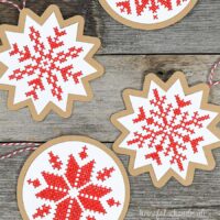 Close up of 4 Scandinavian red and white cross-stitched Christmas ornaments.