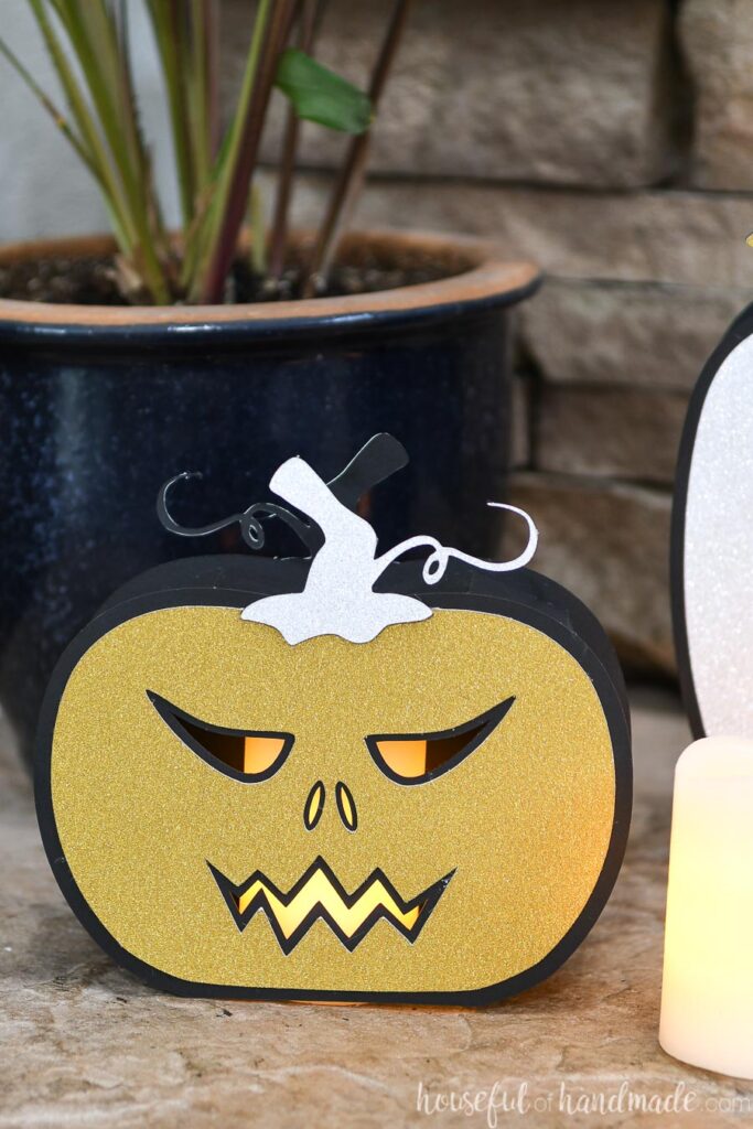 Close up of the short paper jack-o-lantern on the hearth with a candle inside. 