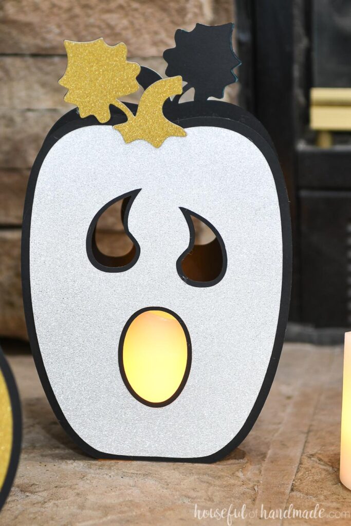 Close up of the ghost faced tall pumpkin lantern with silver glitter cardstock pumpkin face. 