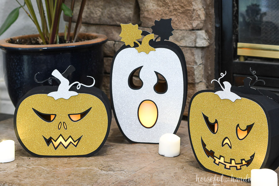 Three Halloween paper lanterns that look like jack-o-lanterns with flameless candles inside.